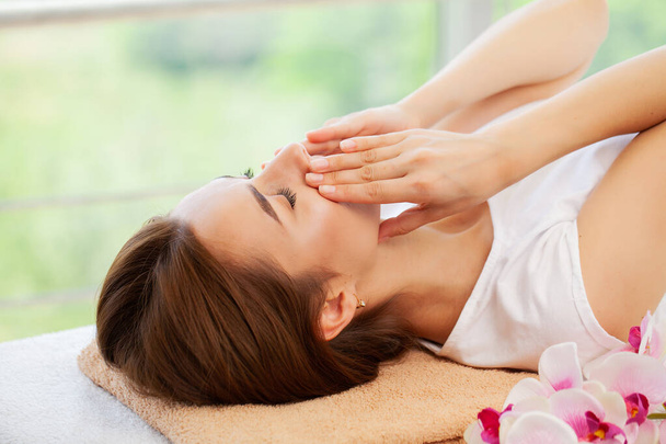 Молода жінка насолоджується масажем обличчя в спа-салоні
 - Фото, зображення