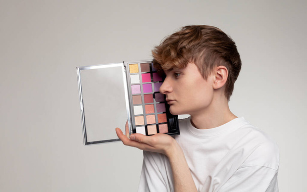 handsome guy with a palette of colored shadows in his hands - 写真・画像