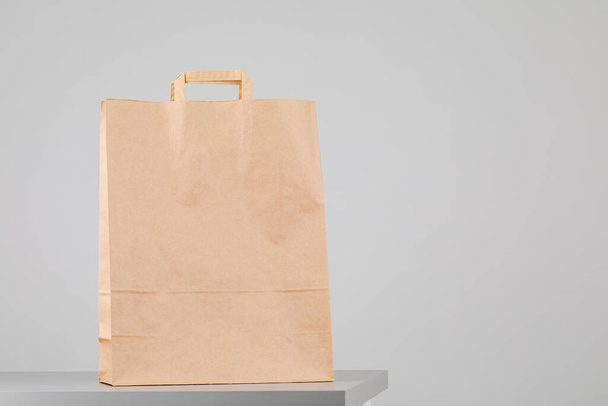 Brown paper bag with handles, empty shopping bag with area for your logo or design, food delivery concept - Photo, Image
