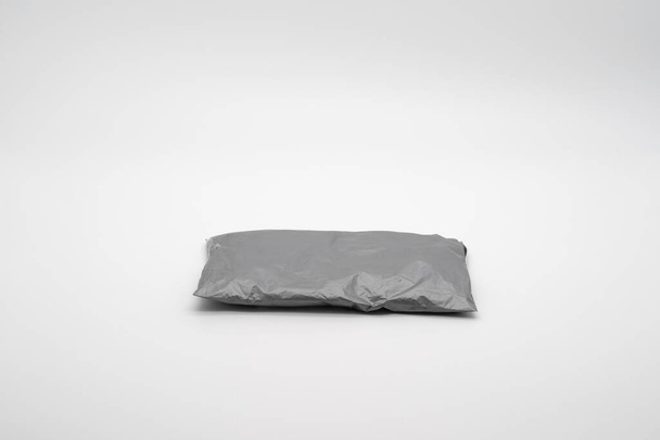 Geïsoleerde Gray Postal Pakket van online winkelen, wordt geleverd aan de koper. Het is opgenomen in het studiolampje voor een witte achtergrond. - Foto, afbeelding