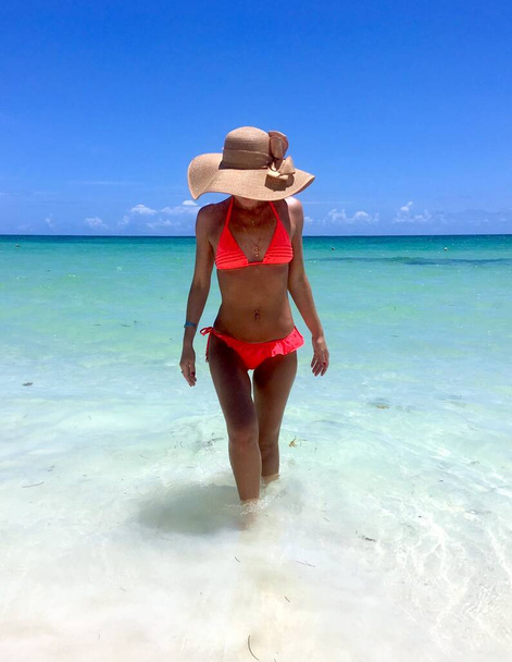 Young woman in a red swimsuit and a hat in the ocean in the tropics  - Фото, изображение