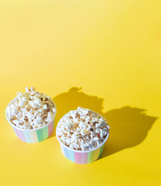 Popcorn in a cardboard box on a yellow background. Popcorn on a yellow background. Fast food. Space for text - Foto, afbeelding