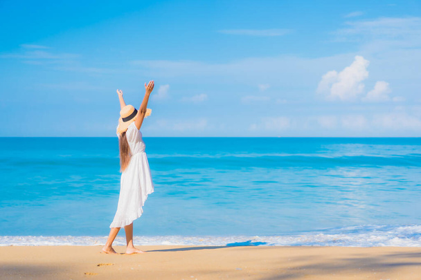Πορτρέτο όμορφη νεαρή Ασιάτισσα γυναίκα χαλαρώστε χαμόγελο αναψυχής γύρω από θάλασσα θάλασσα ωκεανό παραλία με λευκό σύννεφο σε μπλε ουρανό σε ταξιδιωτικές διακοπές - Φωτογραφία, εικόνα