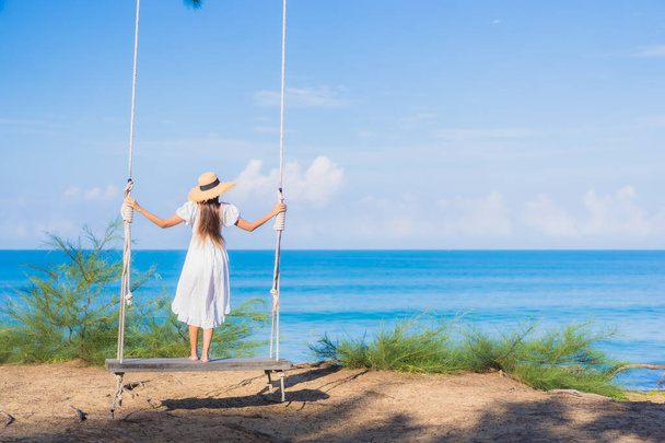 retrato hermosa joven asiático mujer relax sonrisa en swing alrededor playa mar océano para naturaleza viaje en vacaciones - Foto, Imagen