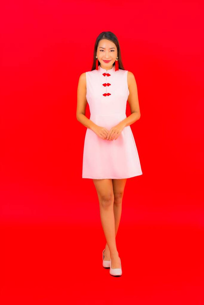 Retrato hermosa joven mujer asiática desgaste chino nuevo año ropa sobre fondo rojo - Foto, imagen