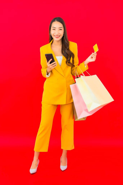 Retrato hermosa joven asiática mujer con un montón de bolsa de compras tarjeta de crédito y teléfono móvil - Foto, imagen