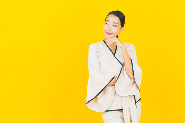 Retrato hermosa joven negocio asiático mujer con sonrisa y acción amarillo fondo - Foto, imagen