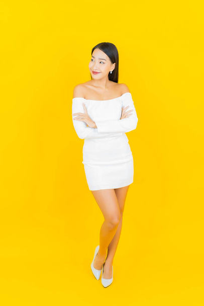 Portrait beautiful young business asian woman with smile and action yellow background - 写真・画像