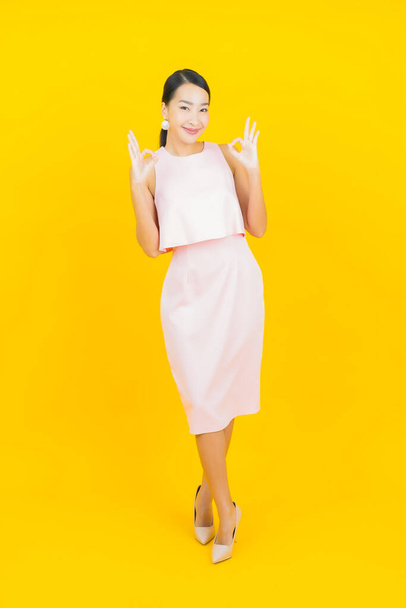 Portrait beautiful young asian woman smile with action on yellow color background - Valokuva, kuva