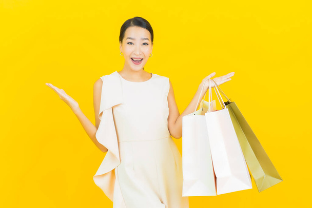 Portrait beautiful young asian woman smile with shopping bag on yellow color background - Foto, afbeelding