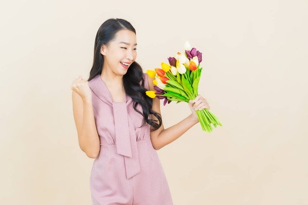 Portrait beautiful young asian woman smile with flower on color background - 写真・画像