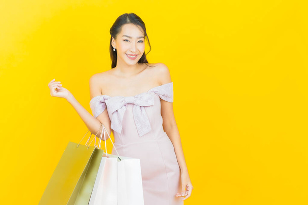 Retrato hermosa joven mujer asiática sonrisa con bolsa de compras en el fondo de color - Foto, Imagen