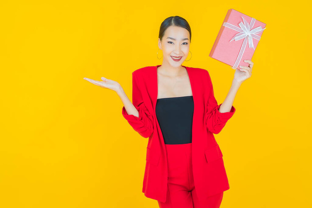 Portré gyönyörű fiatal ázsiai nő mosoly piros ajándék doboz színes háttér - Fotó, kép