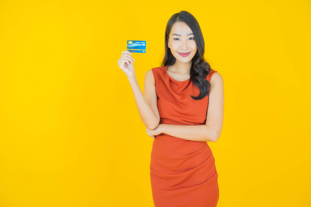Portrait belle jeune femme asiatique sourire avec carte de crédit sur fond de couleur - Photo, image