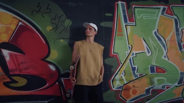 Cheerful man having break after training at skatepark. Teen holding skateboard.  - Footage, Video