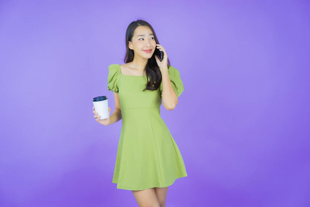 Portrait belle jeune femme asiatique sourire avec téléphone portable intelligent sur fond de couleur - Photo, image