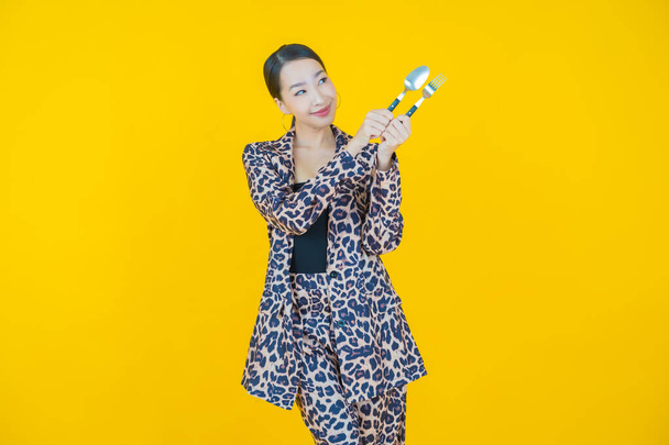 Portrait beautiful young asian woman smile with spoon and fork on color background - 写真・画像