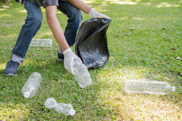 zbieranie śmieci, ręce człowieka podnieść plastikowe butelki, umieścić śmieci w czarnych workach na śmieci do czyszczenia w parkach, uniknąć zanieczyszczenia, być przyjazny dla środowiska i ekosystemu. - Zdjęcie, obraz