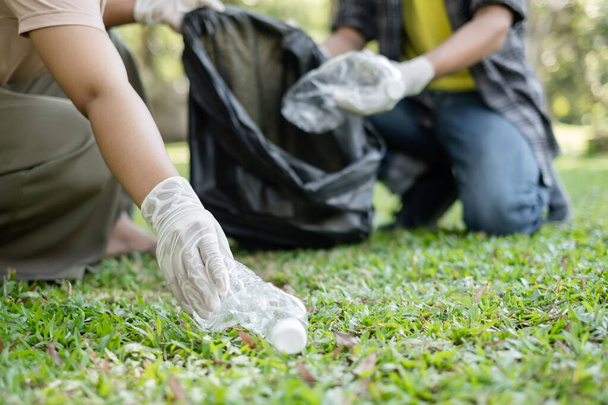 garbage collection, volunteer team pick up plastic bottles, put garbage in black garbage bags to clean up at parks, avoid pollution, be friendly to the environment and ecosystem. - Foto, Imagem