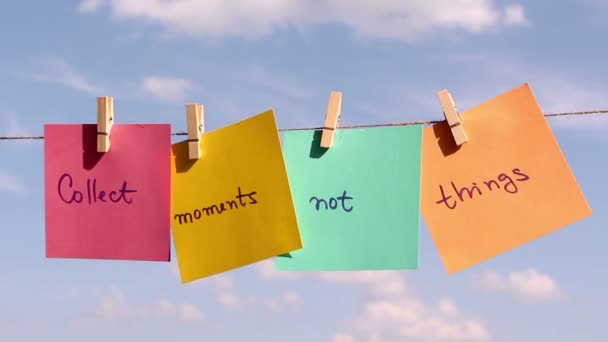 Zdanie "Zbieraj chwile nie myśli" na kolorowy papier ściągnięty na liny. Koncepcja pozytywnego myślenia - Materiał filmowy, wideo