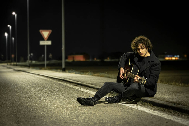 Musician with Acoustic Guitar alone in the Sidewalk at night - Photo, image