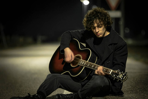 Musician with Acoustic Guitar alone in the Sidewalk at night - Foto, Imagen