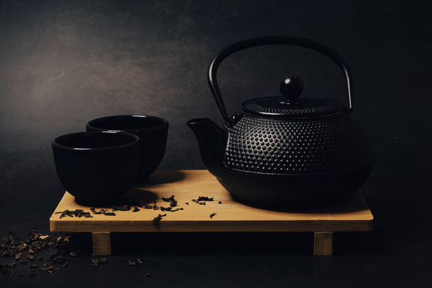 black ceramic teapot and cups on wooden table. selective focus - Фото, изображение