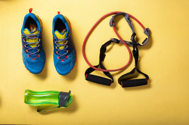 Zapatillas de correr y bandas elásticas para fitness. Cardio con expansor de goma. Fondo amarillo. - Foto, Imagen