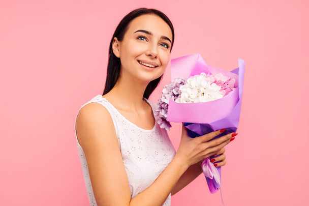 beautiful woman with rose flowers in her hands. Woman on a pink background, celebrating mother's day. March 8. - Foto, afbeelding