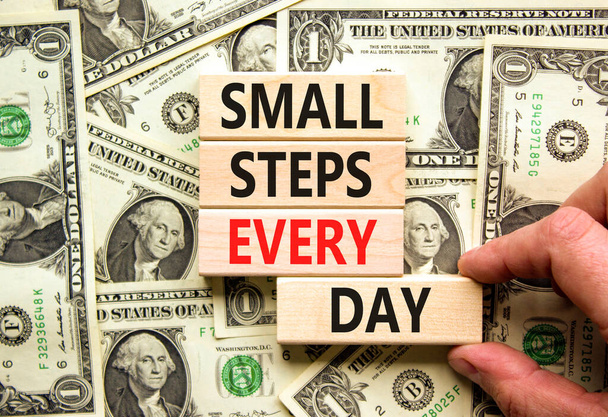 Small steps every day symbol. Concept words Small steps every day on wooden blocks. Businessman hand. Beautiful background from dollar bills. Small steps every day business concept. Copy space. - Fotografie, Obrázek