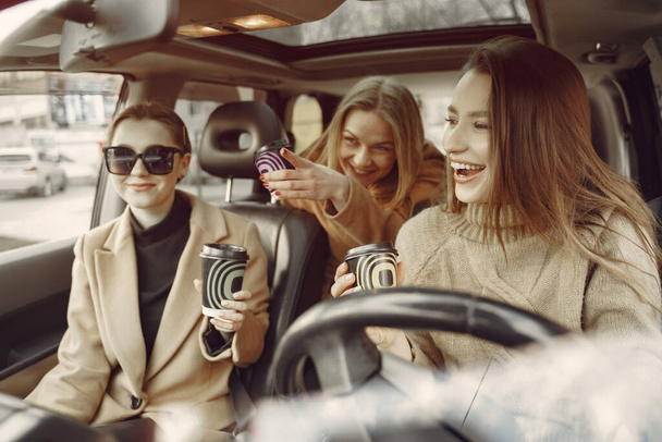 Three girls sitting inside the car and drinking a coffee - Valokuva, kuva