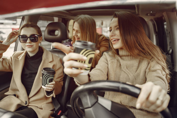 Three girls sitting inside the car and drinking a coffee - 写真・画像