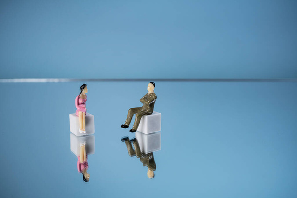 some miniature people in relation to each other on a mirror surface - Foto, Imagen