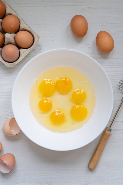 cooking process, eggs in a white bowl on the kitchen table, flat view, breakfast concept  - Fotoğraf, Görsel