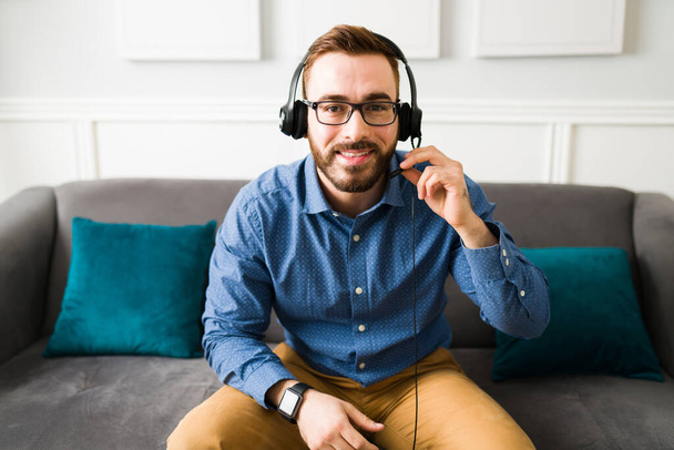 Attractive professional man wearing a headset while working remotely at home as a virtual assistant - Foto, imagen