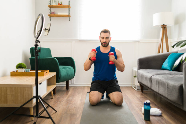 Handsome trainer live streaming a workout. Virtual coach exercising and recording a video  - Фото, зображення