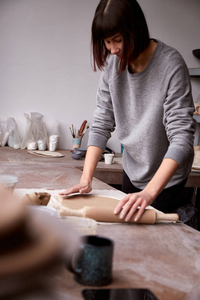 Ceramista donna che lavora nello studio di ceramica. Le mani sporche di argilla del ceramista. Processo di creazione di ceramica. Maestro ceramista lavora nel suo studio - Foto, immagini