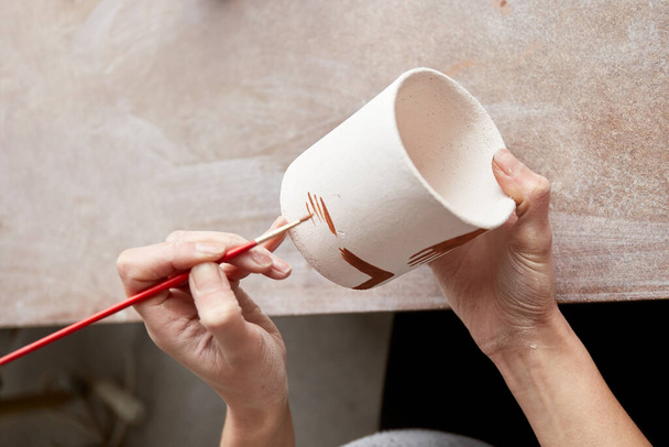 Kobieta ceramistka pracująca w pracowni garncarskiej. Ręce Ceramika brudne od gliny. Proces tworzenia ceramiki. Mistrzyni ceramiki pracuje w swoim studio - Zdjęcie, obraz