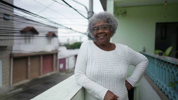 Een zwarte senior vrouw portret staan buiten glimlachen op camera - Foto, afbeelding