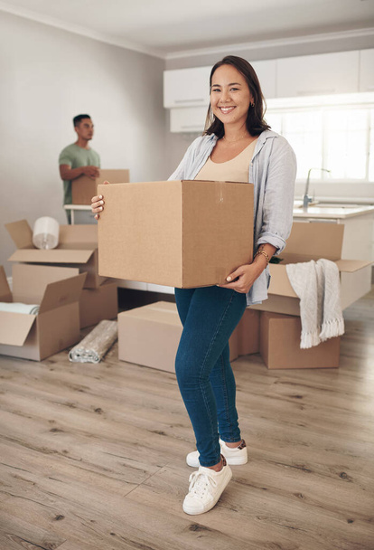 Home ownership is a feeling that makes lifes daily grind worth facing. Shot of a woman holding a box while moving into her new home with her partner. - Photo, Image