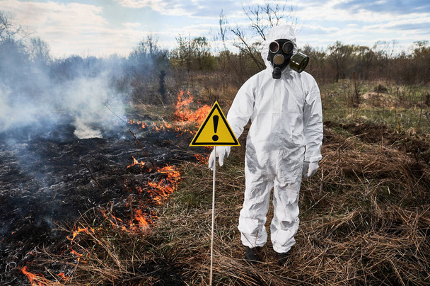 Ecologista bombeiro em máscara de gás trabalhando em campo com fogo selvagem. - Foto, Imagem