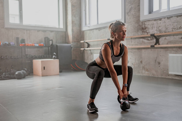 Athletic woman working with dumbbell in gym - Photo, Image