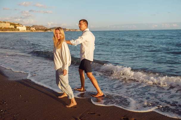 Full-length φωτογραφία του ευτυχισμένου ζευγαριού με τα πόδια κατά μήκος της παραλίας - Φωτογραφία, εικόνα