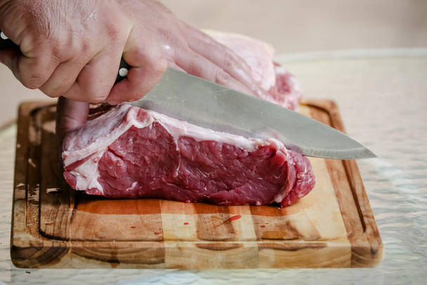 Arka planda keskin bıçakla masada sığır eti kesiyor.. - Fotoğraf, Görsel