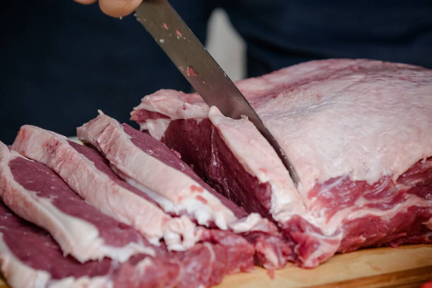 Cutting beef on the table with sharp knife with landscape background. - Photo, Image