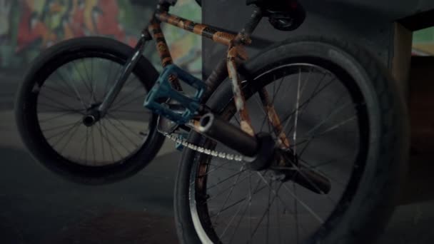 Bmx bike parking against ramp at skatepark graffiti wall. Bicycle wheel spinning - Footage, Video