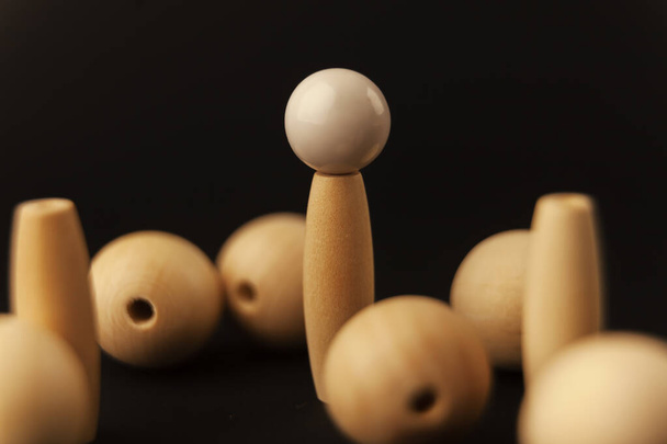 wooden balls and white ball on cylinder on black background, alone against all, close up - Photo, Image