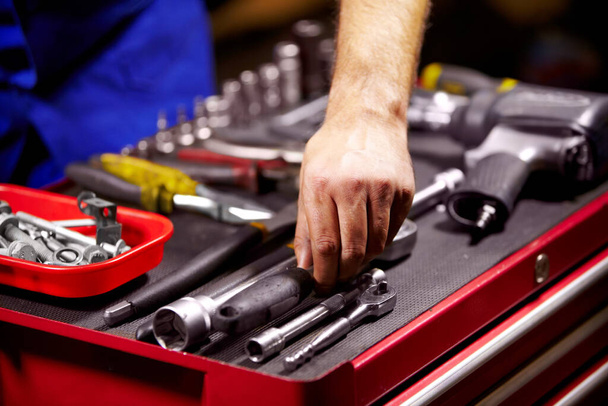 Encontrar la herramienta perfecta. Imagen recortada de las manos de un hombre agarrando una herramienta de su caja de herramientas. - Foto, imagen