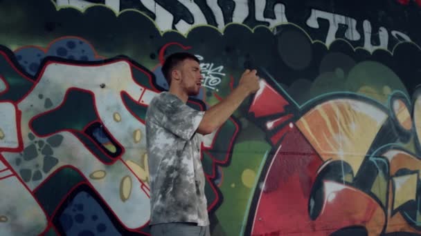 Jongeman schieten video op mobiele telefoon voor blog op skate park met graffiti. - Video