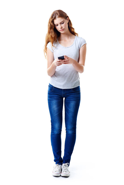 Mantenerse en contacto. Estudio de larga duración de una joven mujer uisng su teléfono móvil sobre un fondo blanco. - Foto, imagen